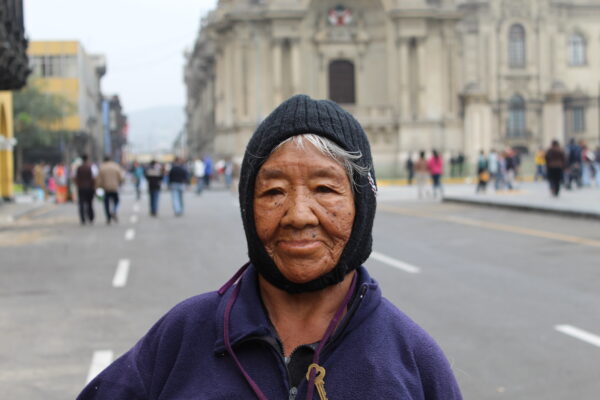 A close up of a woman wearing a black hat standing in front of a blurred city background