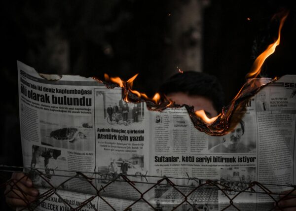 a person reading a newspaper that is on fire