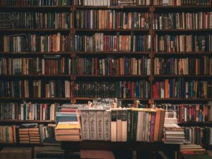 books stacked on table and rows at library